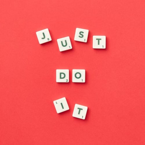 Motivational phrase 'Just Do It' spelled with Scrabble letters on a red background.